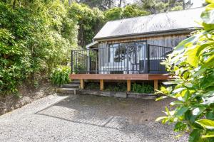 una casa con terraza y banco en Bushside Cottage - Akaroa Holiday Home, en Akaroa