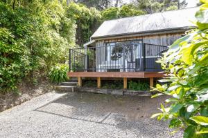 une maison avec une terrasse et un banc dans l'établissement Bushside Cottage - Akaroa Holiday Home, à Akaroa