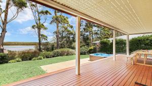 a deck with a view of the water and trees at Sandy C in Culburra Beach