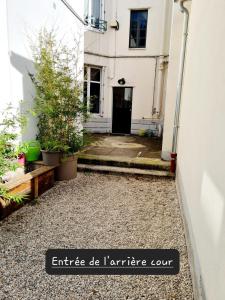 une entrée à un bâtiment blanc avec des plantes dans une cour dans l'établissement Appartement calme et pratique., à Tours