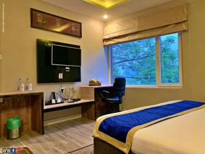 a bedroom with a bed and a desk and a window at Hotel Runway Inn in Pura Raghunāth