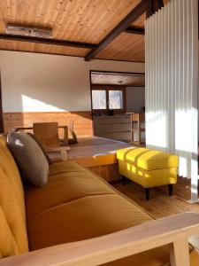 sala de estar con sofá y taburete amarillo en Tamanegi House luxury 4 bedroom Ski Chalet en Nozawa Onsen