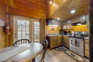 cocina con armarios de madera, mesa y comedor en Misty Mountain Cabin en Gatlinburg