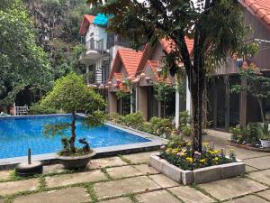 a garden with a swimming pool and trees and flowers at Tam Coc Hao Hao Homestay in Vũ Lâm