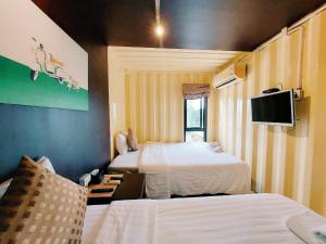 a hotel room with two beds and a tv at Retro Box Hotel Chumphon in Chumphon