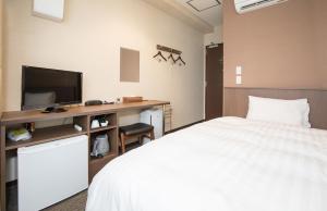 a bedroom with a bed and a desk with a television at Kur and Hotel Isawa in Fuefuki