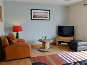 a living room with a chair and a tv at Shoemakers Steading in Hopeman