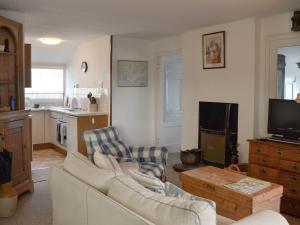 a living room with a couch and chairs and a tv at Thalassa in Pagham