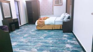 1 dormitorio con 1 cama y alfombra azul en غرف الصفا الشهري, en Jazan