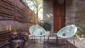 two white chairs sitting on a patio next to a building at La Casa de María 11:11 in Chemuyil