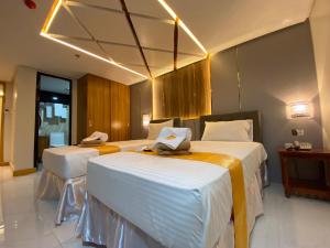 Habitación de hotel con 2 camas, mesa y sillas en NGN Gran Hotel, en Tuguegarao