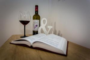 an open book and a glass of wine on a table at Centrum red apartament in Wałbrzych
