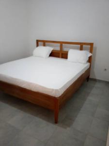 Iknews Appart Dakar في داكار: سرير خشبي مع شراشف بيضاء في الغرفة