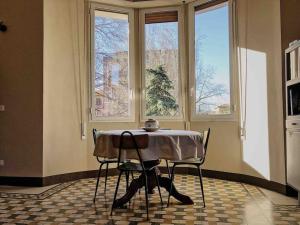 a table and chairs in a room with windows at Appartamento design dèco in Bologna
