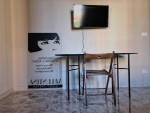 a table with a chair and a television on a wall at Appartamento design dèco in Bologna