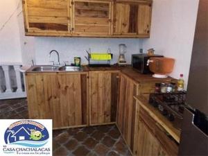 eine Küche mit Holzschränken und einem Waschbecken in der Unterkunft COQUITO HOUSE CHACHALACAS in Chachalacas