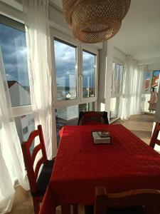 a dining room with a red table and windows at Precioso apartamento con piscina en la playa in Mogro
