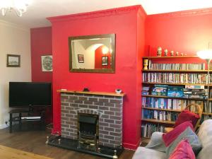 a living room with a fireplace and a red wall at Isabella Cottage in Heddon on the Wall