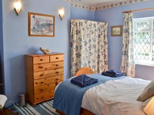 a bedroom with a bed and a dresser and a window at Isabella Cottage in Heddon on the Wall