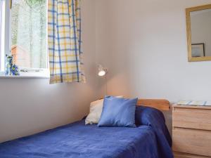a bedroom with a blue bed and a window at Stonecot in Wootton Bridge