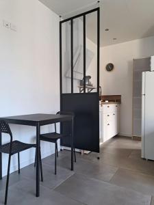 eine Küche mit einem schwarzen Tisch und einem Kühlschrank in der Unterkunft Studio dans maison avec jardin et balcon, au calme in Sérézin-du-Rhône