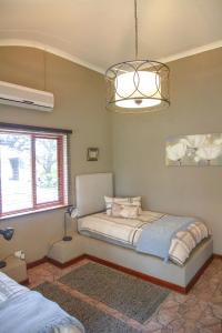 a bedroom with a bed and a chandelier at Klippan River Lodge in Groblersbrug