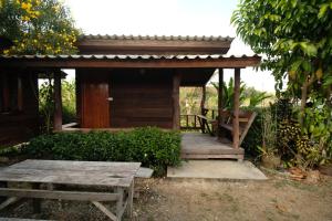 Cabaña de madera con banco y mesa en Na mong Homestay, en Nan