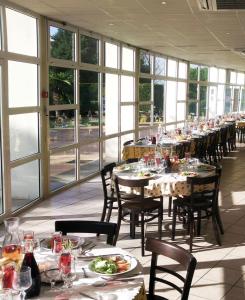 une grande salle à manger avec des tables, des chaises et des fenêtres dans l'établissement Hôtel Residence Les Aiguades, à Port-de-Bouc