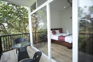 a balcony with a bed and a table and chairs at Villa 75 in Vagamon