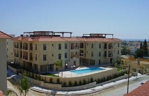 a large building with a pool in front of it at Mazotos Panoramic Village in Mazotos