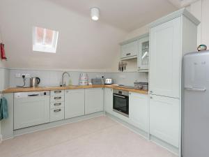 een keuken met witte kasten en een koelkast bij Stable Yard Cottage in Selborne