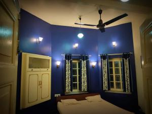 a blue room with a bed and two windows at OH Kolkata - Sutanuti Homestay in Kolkata