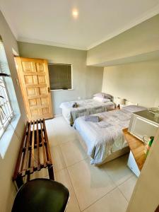 Habitación con 2 camas y una silla. en Wamelia Guesthouse, en Bloemfontein