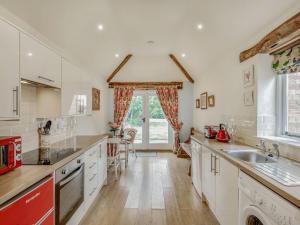 a large kitchen with white cabinets and a large window at The Stables in Laneham