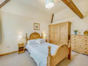 a bedroom with a wooden bed and a wooden dresser at The Stables in Laneham