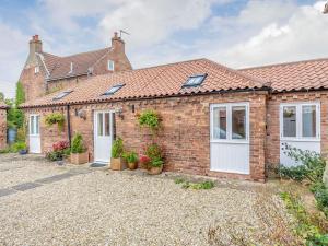 a brick house with white doors and potted plants at The Stables in Laneham