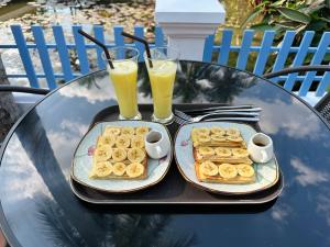 uma bandeja de waffles e dois copos de sumo de laranja em Sadakham Hotel em Luang Prabang