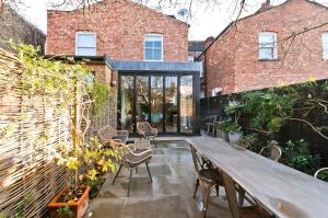 un patio al aire libre con mesa de madera y sillas en Interior designed house with garden in North West London by UnderTheDoormat en Londres