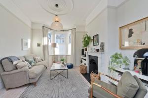 a living room with a couch and a fireplace at Interior designed house with garden in North West London by UnderTheDoormat in London