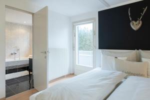 - une chambre avec un grand lit blanc et une salle de bains dans l'établissement Ferienwohnung Alprima, à Vandans