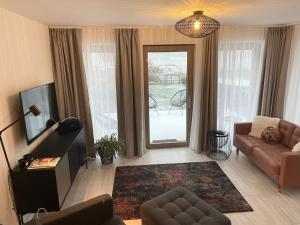 a living room with a couch and a tv and a window at Fotel Dunakanyar in Nagymaros