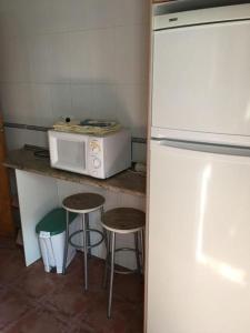 cocina con encimera con microondas y taburetes en Casa Rural Concejo 1 en La Adrada