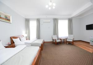 a hotel room with two beds and a table and chairs at Khujand Grand Hotel in Khujand