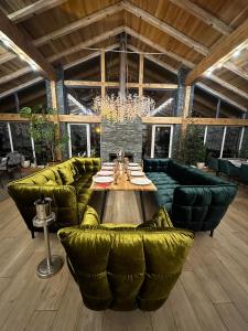 Großes Zimmer mit einem Tisch und grünen Sofas. in der Unterkunft Парк-готель Щастя in Schidnyzja