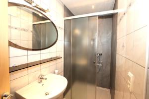 La salle de bains est pourvue d'un lavabo et d'une douche avec un miroir. dans l'établissement Ferienhaus Brandacher, à Rohrberg