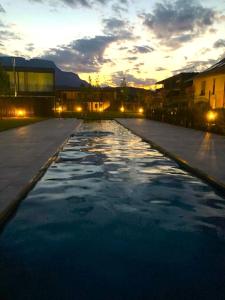 a large pool of water with the sunset in the background at New Great Apartment Bolzano with 25m pool in Bolzano