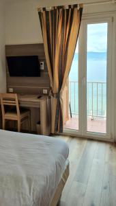 - une chambre avec un lit, une télévision et un balcon dans l'établissement Hôtel U Paradisu, à Porticcio