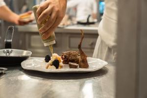 a person is preparing food on a plate on a counter at Le Manoir du Lys, The Originals Relais (Relais du Silence) in Bagnoles de l'Orne