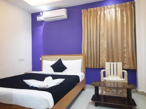 een blauwe slaapkamer met een bed en een tafel bij Hotel Stayinn Thanjavur in Thanjāvūr