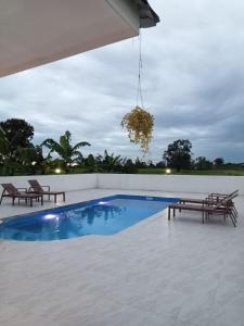 una piscina con 2 bancos y una lámpara de araña en Ranch Seda Mosegaard en Amphoe Khukhan